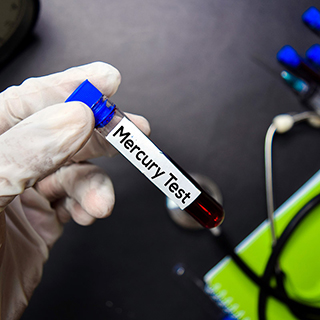hand wearing a rubber glove holding a mercury test vile