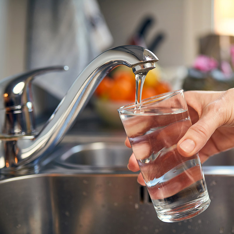 hand holding a glass of water under a kitchen faucet