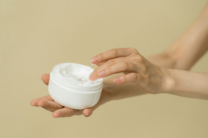 Hand taking sample of cream from container