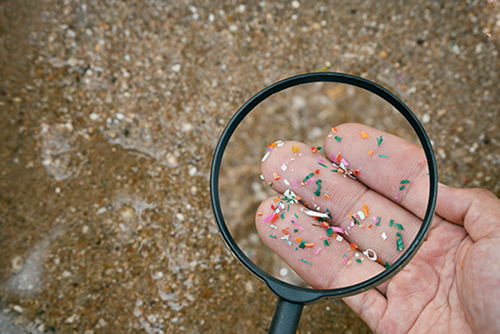 Magnifying glass being used to analyze PFAS in hand