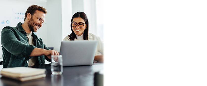 Man and a woman sitting at a table talking about what is on a laptop screen