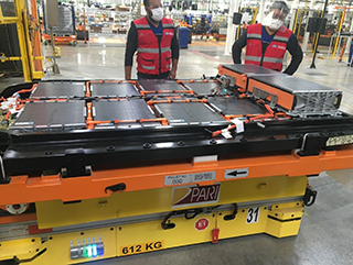 Two people standing in front of large pallet full of batteries