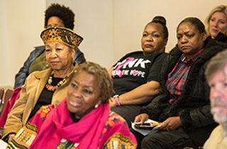 close up of women at community forum with John Schelp's profile in lower right corner