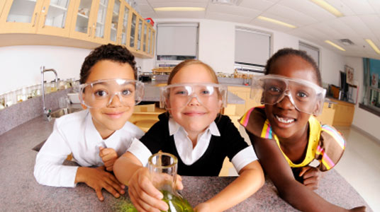 children in a classroom wearing safety goggles