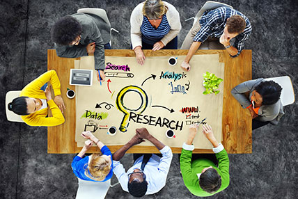 people seated around conference table showing the words research, search, data and analysis
