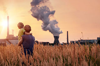 father holding son while looking at smoke stack