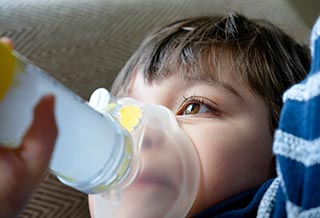 mom watching son while he uses asthma inhaler