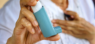 A hand holding an asthma inhaler