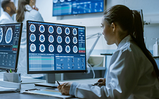 Young female scientist in front of computer monitor conducts modern research on health effects