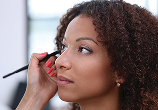 someone applying makeup to an African American woman