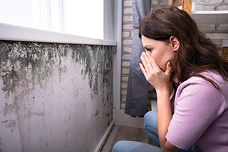 woman gasping at mold on a wall