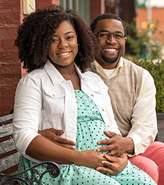 expectant parents seated on bench