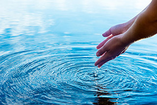 Persona sumergiendo las manos en un lago