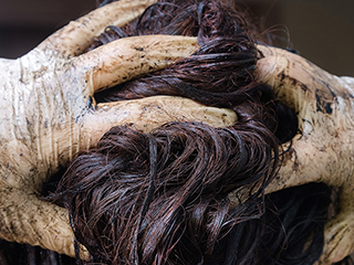 woman with gloved hands running fingers through hair and gloves coated with hair dye