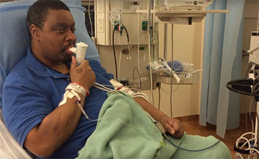 man using an inhaler in a hospital bed