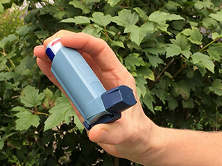 hand holding a blue asthma inhaler