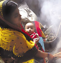 woman holding infant and cooking over fire