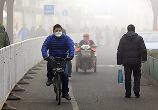 An unidentified man ride a bicycle in smog, in a foggy and hazy day. Beijing issued a red alert for air pollution on Friday, its second red alert this month.  images