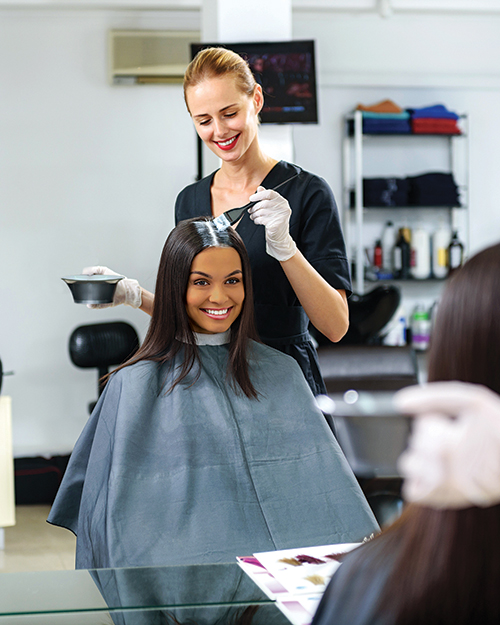 Hairdresser applying hair dye on a woman's hair