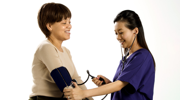 two women smile and take a blood pressure reading