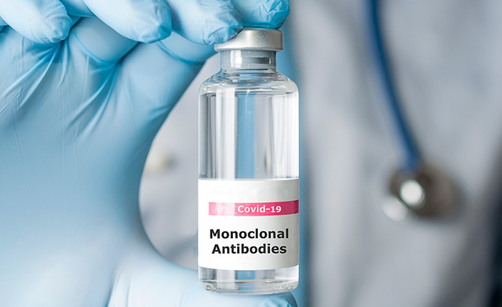 gloved hand holding monoclonal antibodies vial