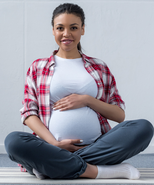 pregnant woman sitting cross-legged, holding her belly