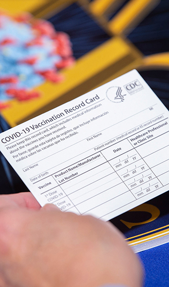 a hand holding a COVID-19 Vaccination Record Card