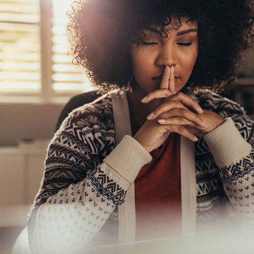 Woman with eyes closed and hands together