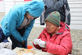 Abigail Nelson with elder and Sivuqaq Working Group member Harriet Penayah dissecting stickleback