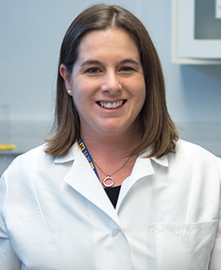 Dana Dolinoy, Ph.D., in a white lab coat