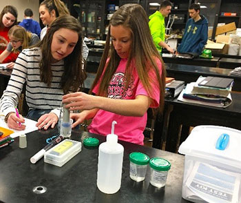Two student scientists using their knowledge to analyza water samples 