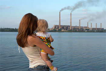 woman and child looking at smoke stacks from a distance 