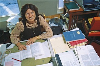 Karen Wetterhahn working on her desk, filled with research data and articles.