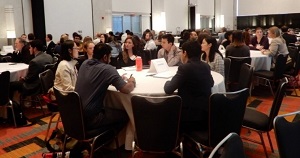 trainees and alumni sitting around multiple tables in a conference room
