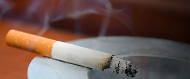 a half burned lit cigarette sitting in an ash trey