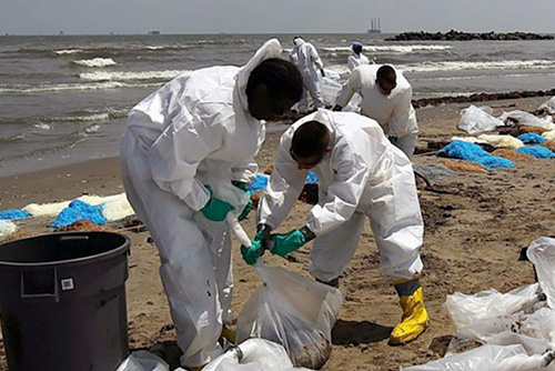 People in hazmat suits picking up debris from the beach