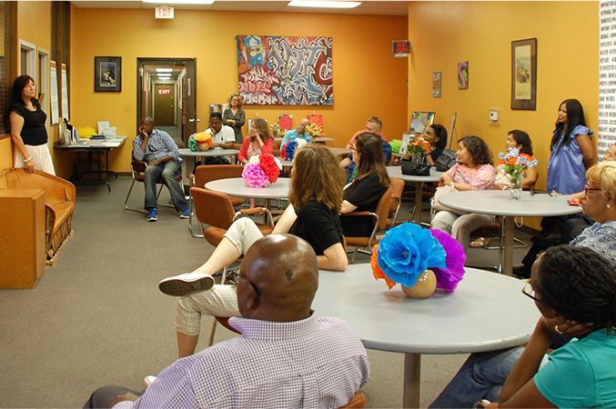 a woman speaking to group of people sitting around tables