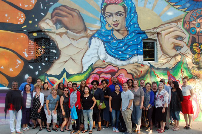 group of people posing for photo in front of a mural