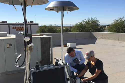 two people on a rooftop looking at some equipment