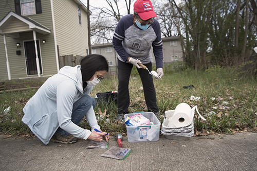 two people collecting soil samples in a neighborhood