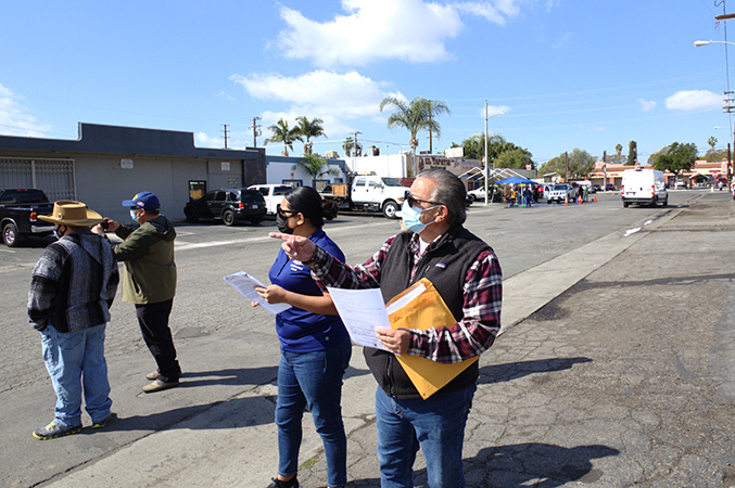 people in a parking lot holding papers and and large envelope