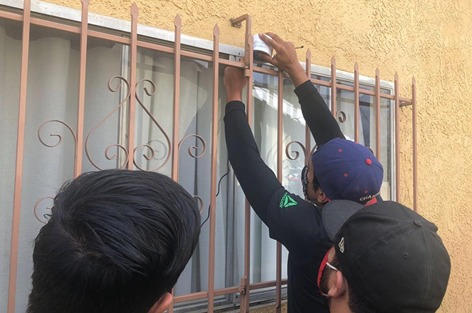 three people installing a sensor on the outside of a window