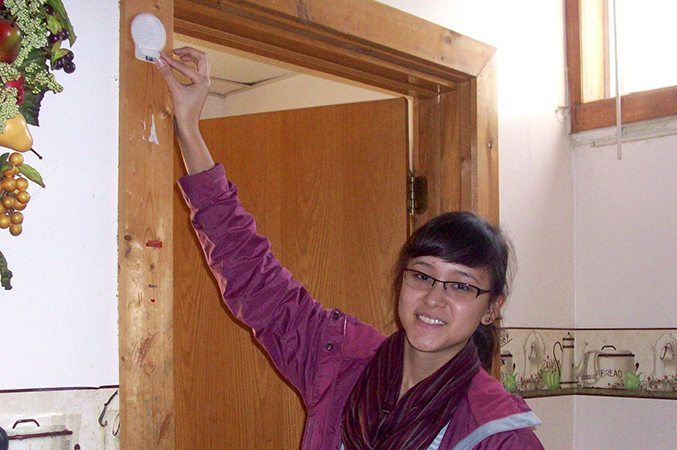a woman touching a device on a doorframe