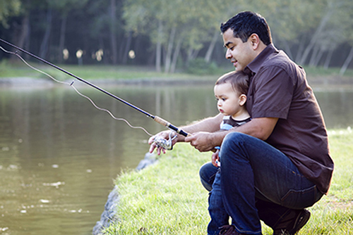man showing child how to hold a fishing pole