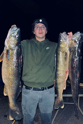 young man holding 3 large fish