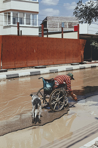 man in a wheelchair next to a flooded street
