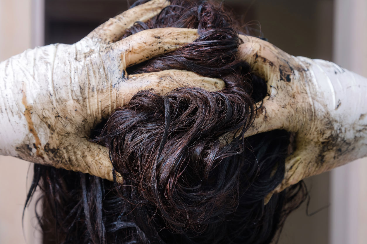 woman with gloved hands running fingers through hair and gloves coated with hair dye
