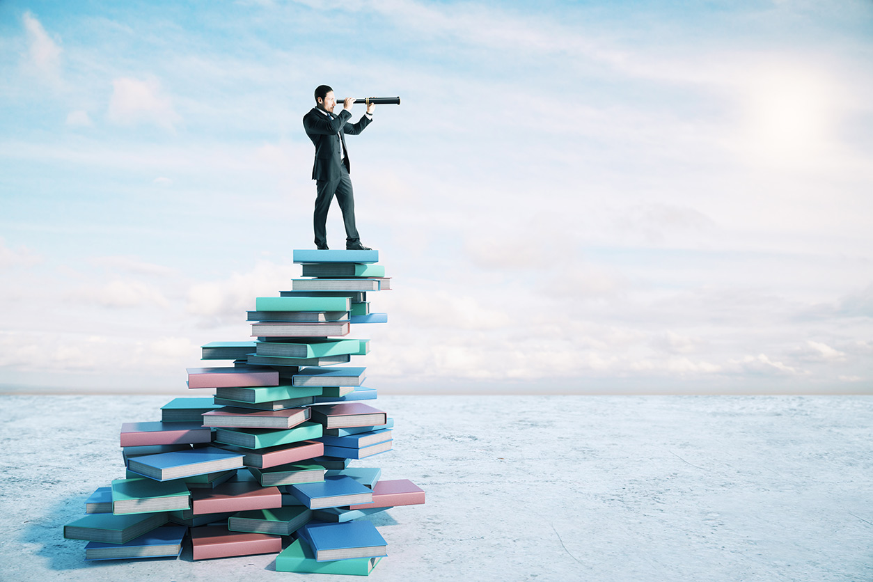 man on book mountain looking through a telescope