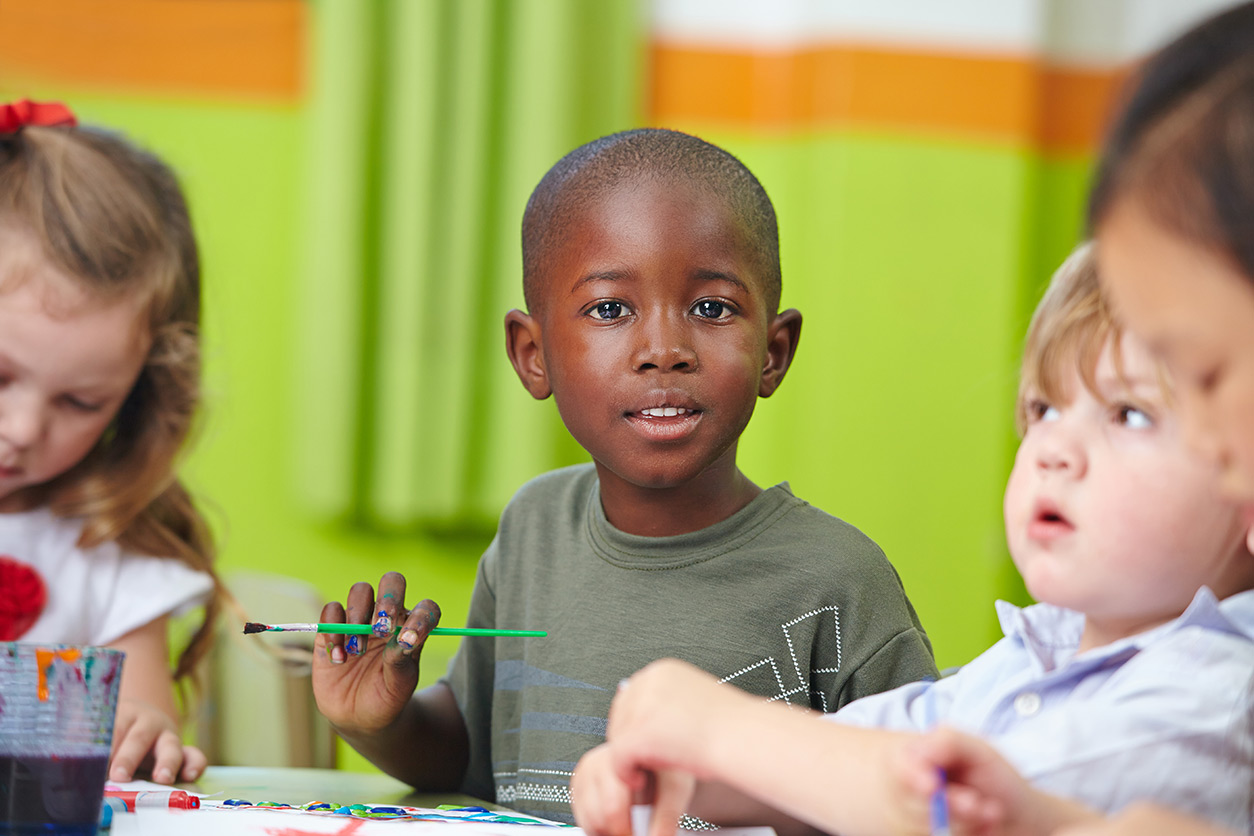 boy holding a paintbrush, looking at us
