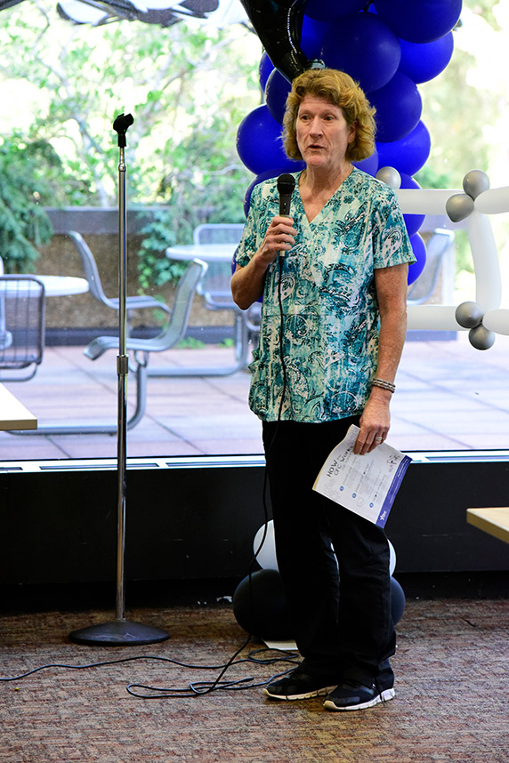 Debra King holding microphone and standing by stage with balloons